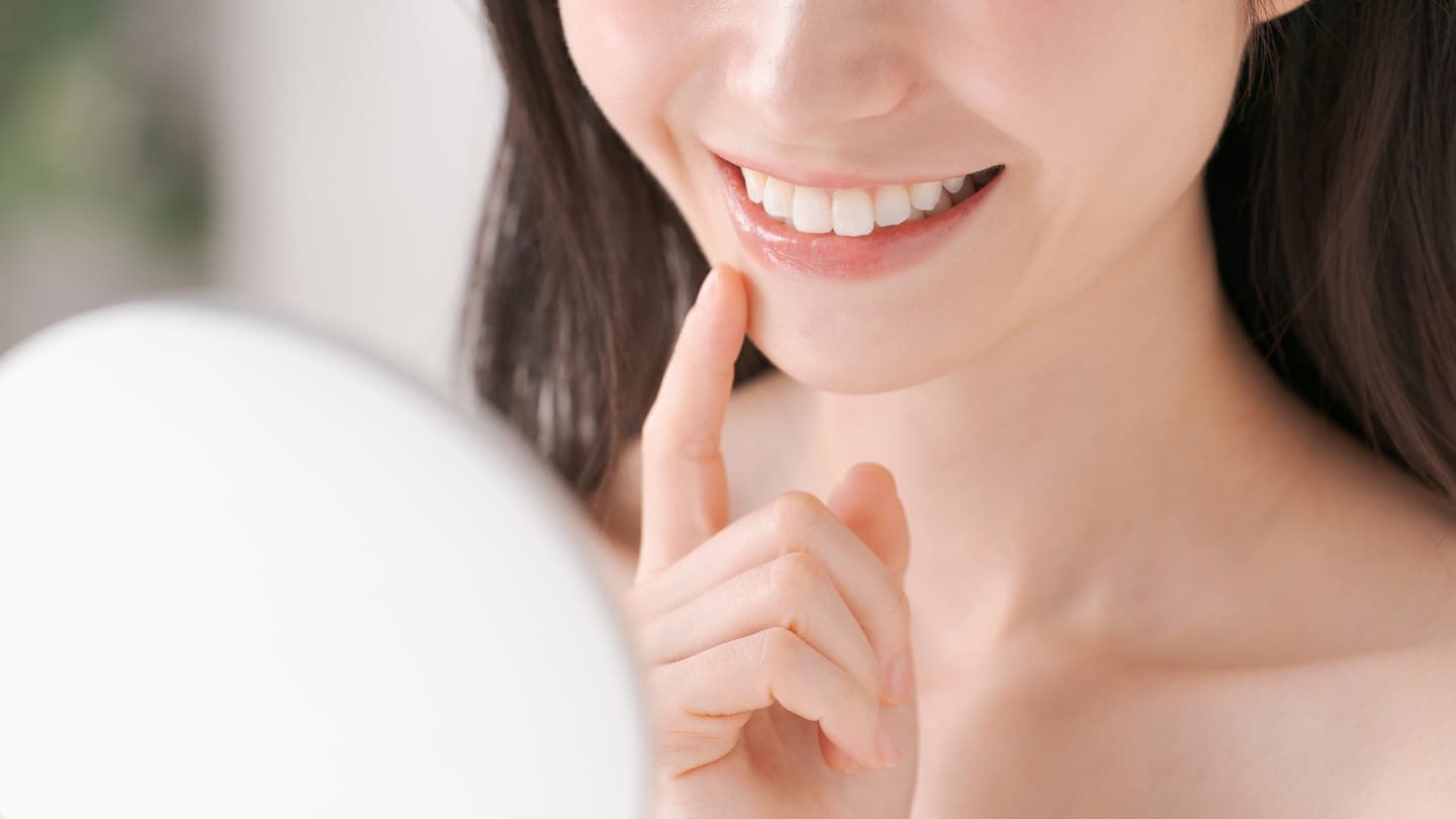 鏡を見て微笑む女性